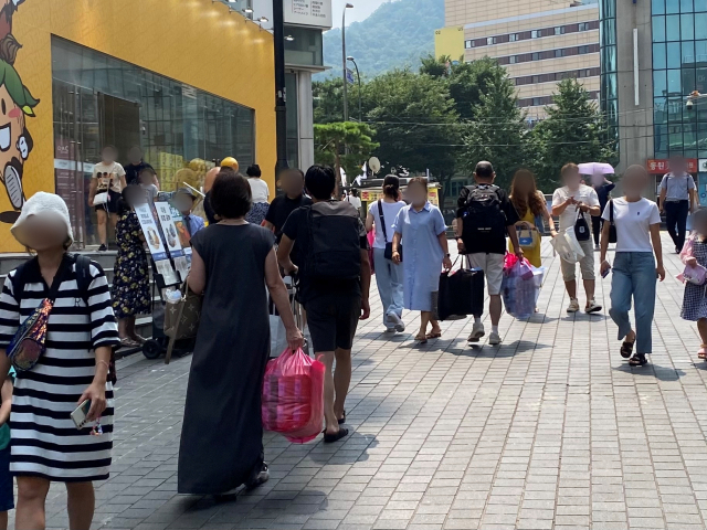 중국인 단체관광객 입국이 재개된 15일 오후 서울 중구 명동 일대에서 관광객들이 양손 가득 물건을 사서 이동하고 있다. 김남명 기자