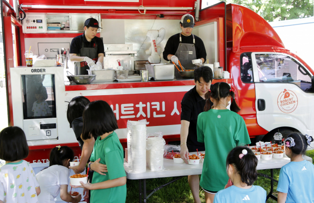 아동복지시설 꿈나무마을 아이들이 두산로보틱스 협동로봇이 튀긴 치킨을 시식하고 있다.