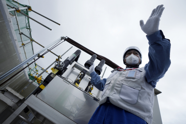 도쿄전력 관계자가 27일 일본 후쿠시마현 후타마에 있는 후쿠시마 제1원자력발전소에서 희석을 완료한 오염수의 샘플을 채취하는 기계를 기자들에게 설명하고 있다. AP 연합뉴스