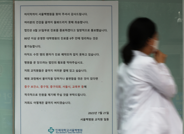 중구 서울백병원이 마지막 진료를 끝으로 폐원하는 31일 의료진이 병원 현관에 붙은 호소문 앞을 지나고 있다. 연합뉴스