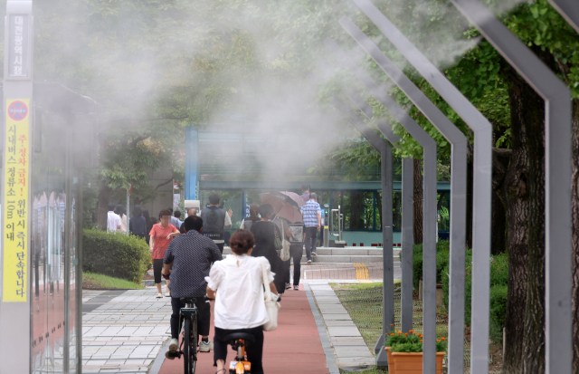 5일 대전시 서구 둔산동 대전시청 앞에 설치된 쿨링포그 아래로 시민들이 지나가고 있다.연합뉴스