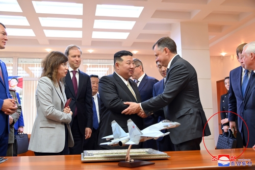 김정은 북한 국무위원장이 15일 러시아 하바롭스크주 콤소몰스크나아무레시의 유리 가가린 전투기 공장을 방문했다고 조선중앙통신이 16일 보도했다. 방문에 동행한 김여정 노동당 부부장이 명품 브랜드 제품으로 추정되는 가방(붉은 원)을 들고 있다. 연합뉴스