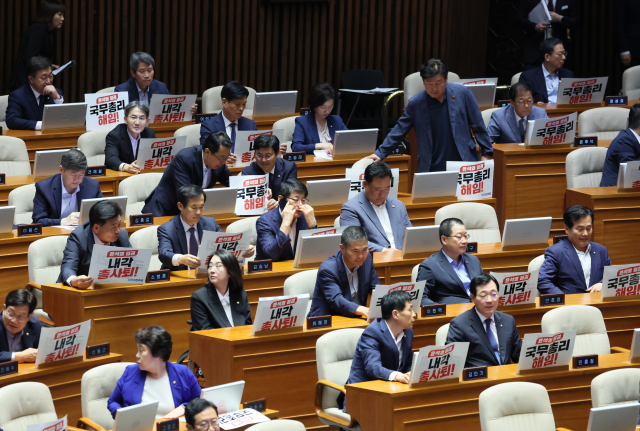 18일 국회에서 열린 본회의에서 더불어민주당 의원들이 국무총리 해임과 내각 총사퇴를 촉구하는 문구를 붙이고 있다. 연합뉴스