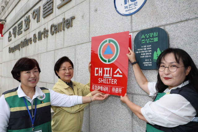 김미경(가운데) 은평구청장과 직원들이 지난 21일 제48주년 민방위대 창설기념행사를 맞아 점자 민방위 대피시설 표지판을 부착하고 있다. 사진제공=은평구