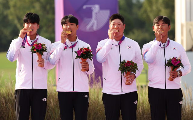 장유빈(왼쪽부터)과 조우영, 임성재, 김시우가 1일 항저우 아시안게임 골프 단체전에서 금메달을 획득한 뒤 시상대에 올라 금메달을 물어보고 있다. 연합뉴스