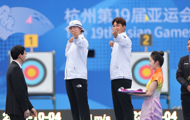 한국 양궁 대표팀의 임시현(왼쪽)과 이우석이 4일 항저우 아시안게임 리커브 양궁 혼성전 우승 뒤 시상식에서 하트를 쏘는 세리머니를 펼치고 있다. 연합뉴스