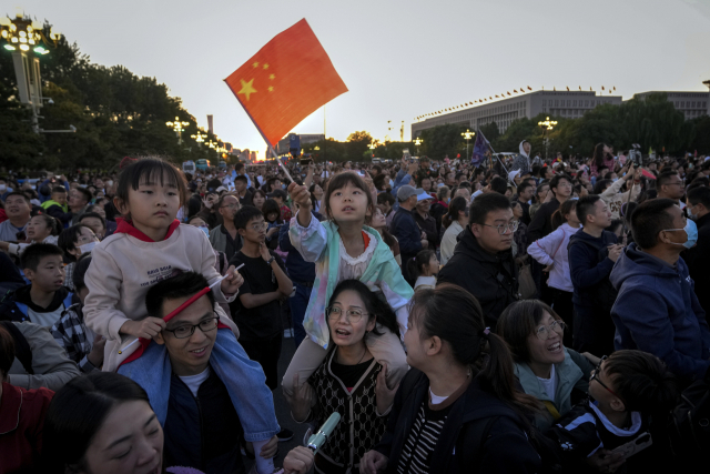베이징 천안문 광장 인근에 1일 국경절 국기 게양식을 보기 위해 운집한 가운데 한 어린이가 국기를 흔들고 있다. 국경절 연휴 기간 중국 내 관광 수요가 크게 늘어나며 경기 회복 기대감도 커지고 있다. AP연