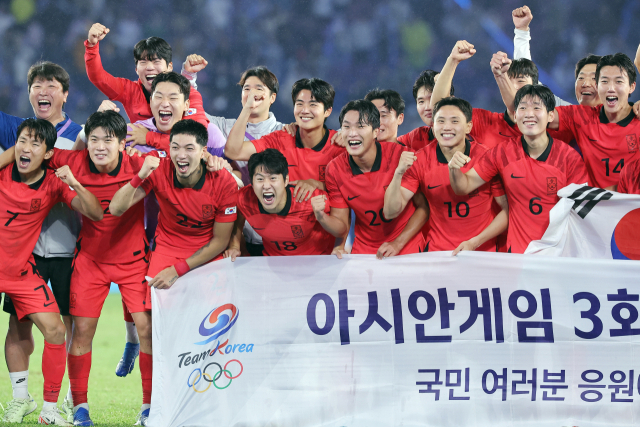 파리 생제르맹 소속 이강인(앞줄 왼쪽 네 번째) 등 한국 축구 대표팀 선수들이 7일 항저우 아시안게임 결승 한일전 승리 뒤 대회 3연패를 자축하는 현수막을 배경으로 환호하고 있다. 연합뉴스