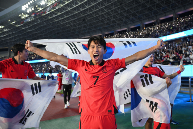 정우영(가운데)이 7일 항저우 아시안게임 남자 축구 금메달을 확정한 뒤 태극기를 들고 포효하고 있다. 사진 제공=대한축구협회