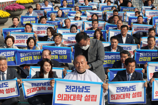 지난 18일 오후 서울 용산 대통령실 앞에서 열린 전라남도 의과대학 신설 촉구대회에서 더불어민주당 김원이 의원이 삭발을 하며 전남도의원 등 참석자들과 구호를 외치고 있다. 연합뉴