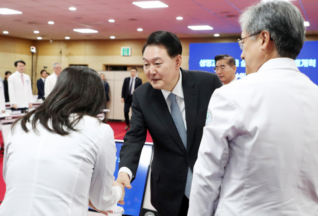 윤석열 대통령이 19일 충북 청주 충북대학교 개신문화관에서 열린 생명과 지역을 살리는 필수의료혁신 전략회의에 입장하며 참석자들과 인사하고 있다. 연합뉴스