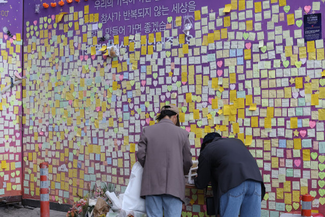 핼러윈 데이를 앞두고 시내 번화가에 인파 밀집이 예상되는 가운데 27일 오후 서울 용산구 이태원 참사 추모 현장을 찾은 시민들이 추모 글귀를 적고 있다. 연합뉴스