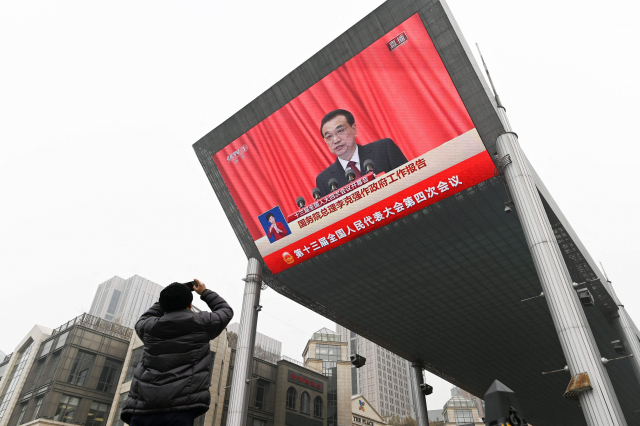 한 남성이 2021년 3월 5일 중국 베이징 인민대회당에서 열린 전국인민대표대회 개막식에서 리커창 당시 총리가 연설하는 모습이 담긴 대형 화면을 휴대폰으로 촬영하고 있다. 중국 매체는 27일 리 전 총리가 심장마비로 사망했다고 보도했다. AFP연합뉴스