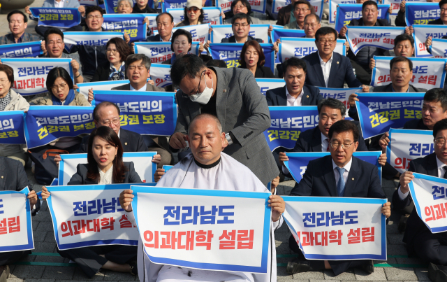 지난 18일 서울 용산 대통령실 앞에서 열린 전라남도 의과대학 신설 촉구대회에서 더불어민주당 김원이 의원이 삭발을 하며 참석자들과 구호를 외치고 있다. 연합뉴스