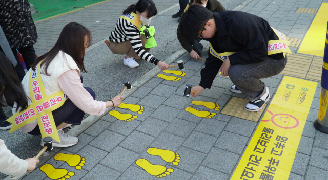 대전교통공사 직원들이 판암초등학교 앞 횡단보도에 ‘노란발자국’스티커를 부착하고 있다. 사진제공=대전교통공사