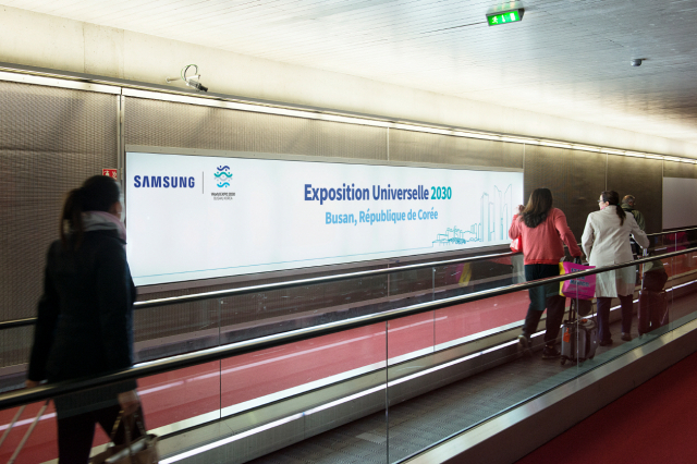 프랑스 파리 샤를드골공항 이용객들이 삼성전자가 설치한 2030 부산세계박람회(부산엑스포) 홍보 문구가 적힌 광고판 앞을 지나고 있다. 사진 제공=삼성전자