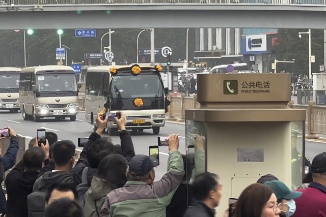 중국 베이징 시민들이 2일 바바오산 혁명공원 인근에서 리커창 전 총리의 운구 차량 행렬을 휴대폰으로 촬영하고 있다. AP연합뉴스