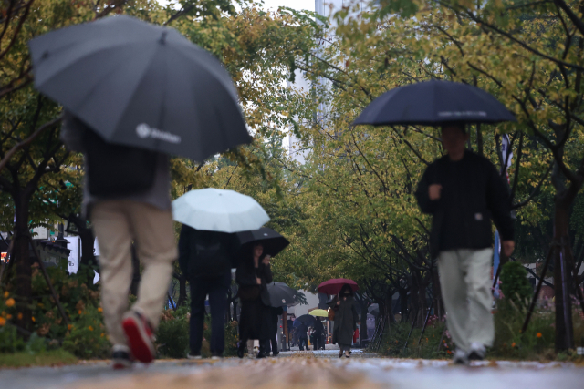 지난달 19일 오전 서울 광화문광장에서 시민들이 우산을 쓴 채 걸어가고 있다. 연합뉴스