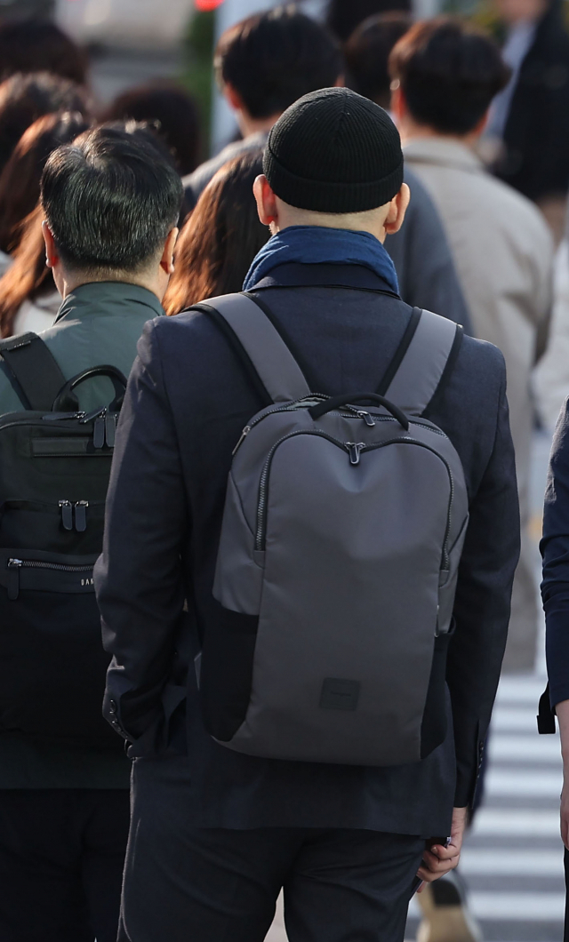지난달 18일 서울 광화문광장에서 한 직장인이 목도리를 두르고 출근하고 있다. 연합뉴스
