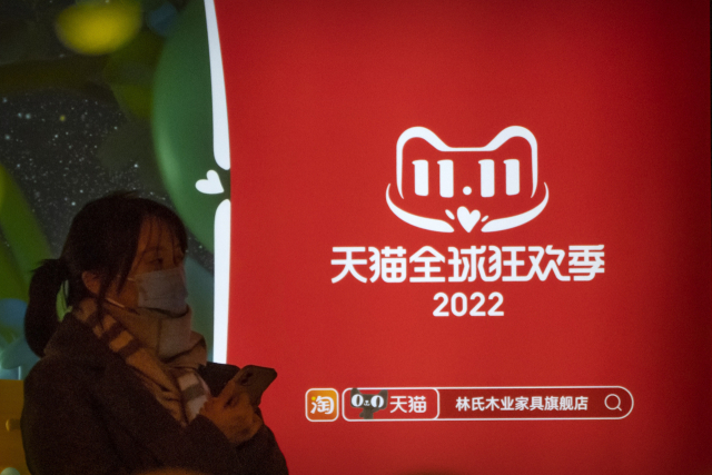 지난해 11월 9일 베이징에서 한 여성이 알리바바그룹의 온라인 쇼핑몰 티몰의 광군제 세일 광고 옆 버스 정류장에서 버스를 기다리고 있다. AP연합뉴스