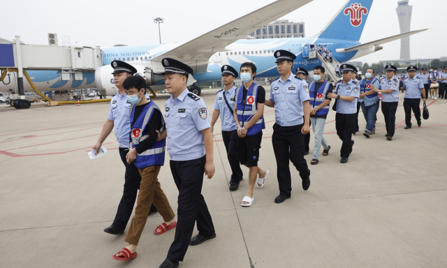 중국 경찰이 9월 11일 허난성 정저우 국제공항에서 라오스에서 도착하는 전세기로 이동한 통신 사기 용의자들을 호송하고 있다. 글로벌타임스