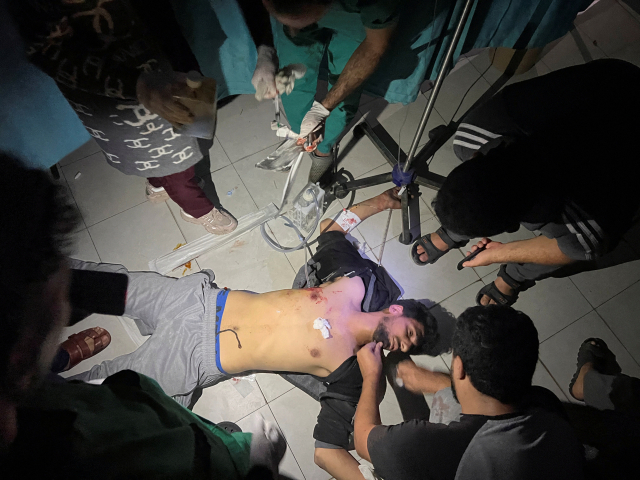 가자지구 알시파 병원 의료진이 16일(현지 시간) 이스라엘군의 공습으로 다친 팔레스타인 남성을 치료하기 위해 휴대전화 플래시를 이용하고 있다. 로이터연합뉴스