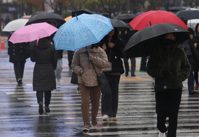 지난 16일 오전 서울 광화문광장 인근에서 갑자기 비가 내리자 시민들이 우산을 쓰고 이동하고 있다. 연합뉴스