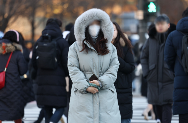 아침 기온이 영하권으로 떨어진 30일 오전 서울 광화문광장에서 시민이 핫팩을 든 채 걸어가고 있다. 연합뉴스