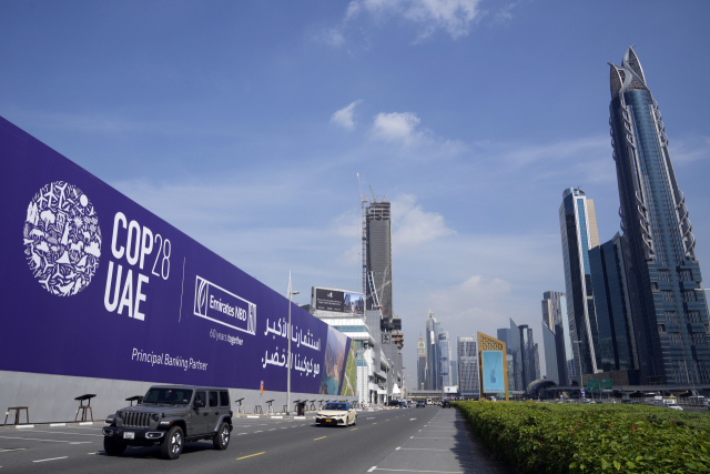 27일(현지시간) 아랍에미리트(UAE) 두바이의 셰이크자이드 고속도로에서 자동차들이 제28차 유엔기후변화협약 당사국 총회(COP28) 광고판을 지나치고 있다. 연합뉴스