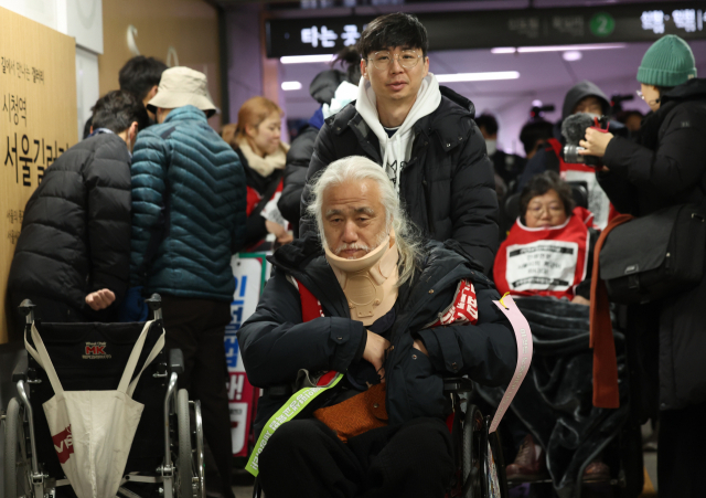 박경석 전국장애인차별철폐연대(전장연) 대표가 11월 30일 오후 시청역 승강장에서'서울시 권리중심일자리 연계사업 폐지 규탄 전국결의대회'를 열고 서울교통공사의 퇴거 요청에 역을 빠져나가고 있다. 연합뉴스