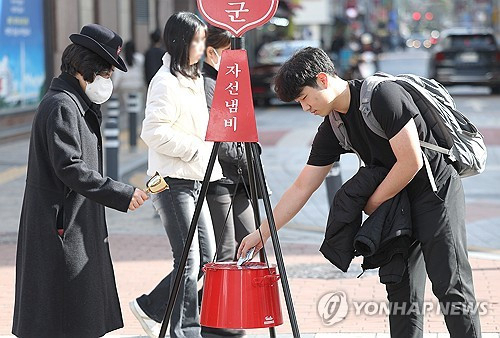 포근한 날씨를 보인 8일 대구 중구 동성로에서 가벼운 옷차림을 한 시민이 구세군 자선냄비에 성금을 넣고 있다. 연합뉴스