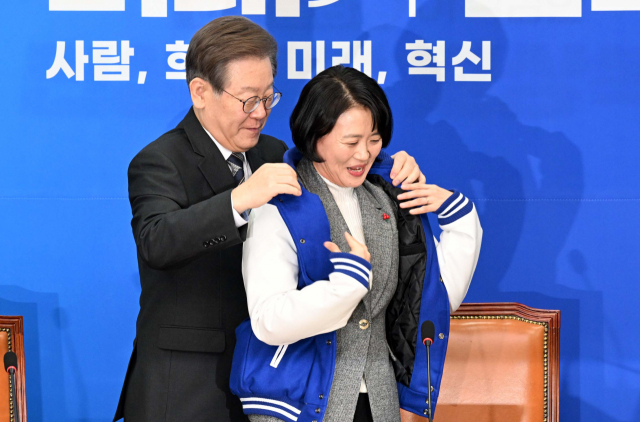 이재명 더불어민주당 대표가 11일 국회에서 열린 1호 인재영입식에서 기후위기 전문가인 박지혜 변호사에게 점퍼를 입혀주고 있다. 권욱 기자 2023.12.11