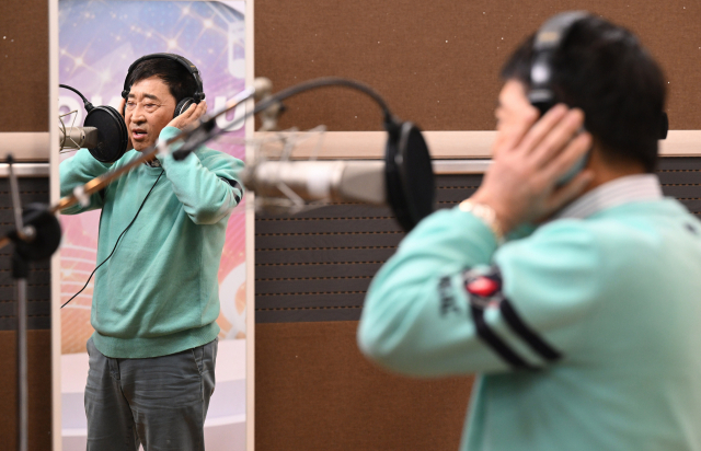 김명환 덕신하우징 회장 겸 가수가 녹음실에서 자신의 대표곡 ‘눈물의 대전역’을 부르고 있다. 오승현 기자