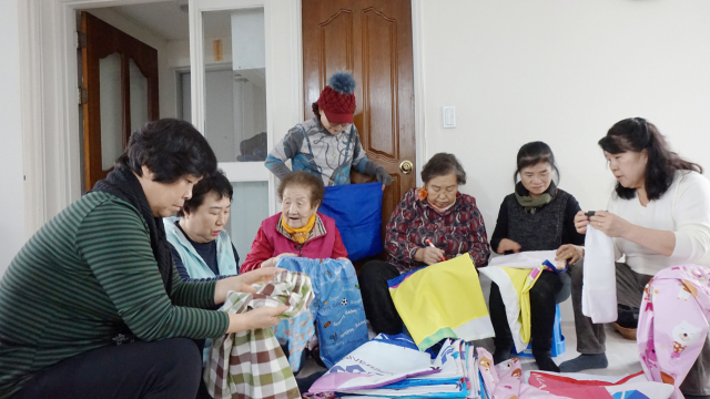 마산합포 할머니 봉사회 회원들이 폐현수막으로 장바구니를 제작하고 있다. 사진 제공=KT