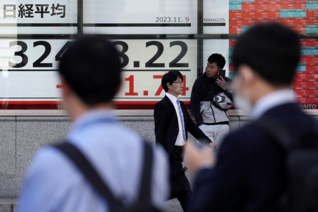일본 도쿄의 증시 전광판 앞으로 직장인들이 지나가고 있다./AP연합뉴스