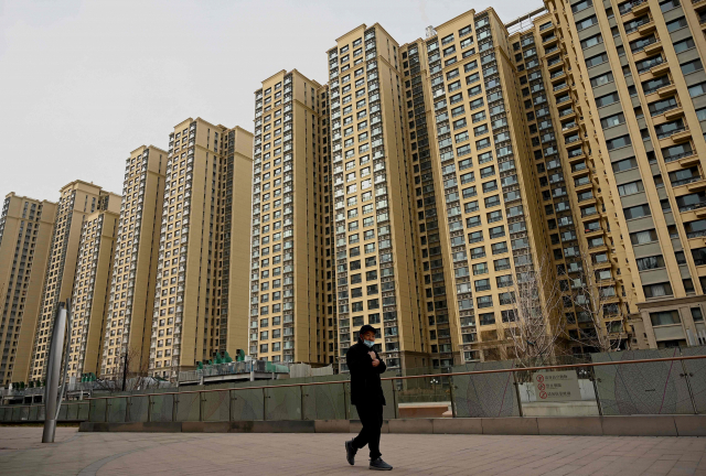 한 중국 남성이 2021년 12월 에버그란데가 지은 베이징의 한 아파트 주택 단지 앞을 지나가고 있다. AFP연합뉴스