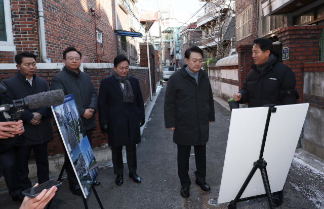 윤석열 대통령이 21일 서울 중랑구의 소규모주택정비 관리지역인 모아타운 사업지를 방문해 오세훈 서울시장으로 부터 현장에 대한 설명을 듣고 있다. 연합뉴스