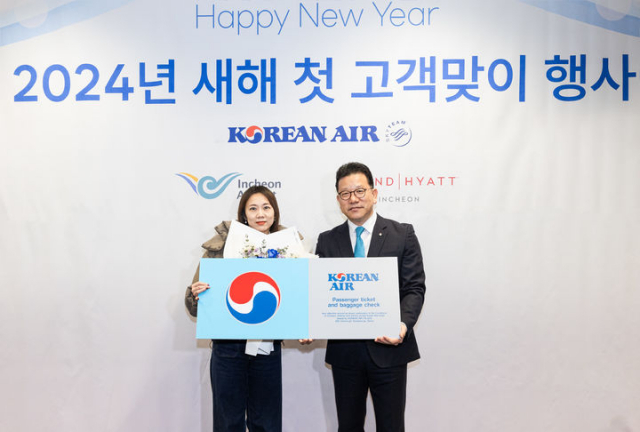 송보영(오른쪽) 대한항공 여객사업본부장이 1일 오전 인천국제공항에서 열린 ‘새해 첫 고객맞이 행사’에서 새해 첫 고객인 중국인 쫑위에 씨에게 기념패와 선물 등을 증정한 뒤 기념촬영을 하고 있다. 사진제공=대한항공