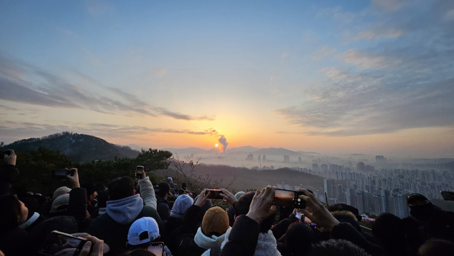 1일 오전 7시 50분께, 일출 명소인 경기도 안양시 망해암을 방문한 시민들이 새해 첫 태양을 휴대전화에 담고 있다. 채민석 기자