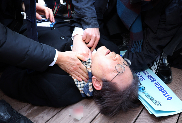 이재명 더불어민주당 대표가 2일 오전 부산 강서구 가덕신공항 부지를 둘러본 뒤 왼쪽 목 부위 피습을 당해 바닥에 누워 병원 호송을 기다리고 있다. 연합뉴스