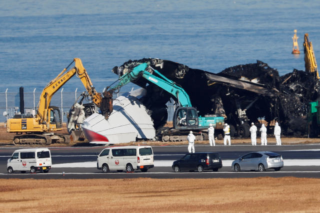 일본 도쿄 하네다공항 활주로에서 해상보안청 항공기와 충돌해 불탄 일본항공(JAL) 에어버스 A350 여객기의 잔해를 5일 관계자들이 치우려 하고 있다. 로이터연합뉴스