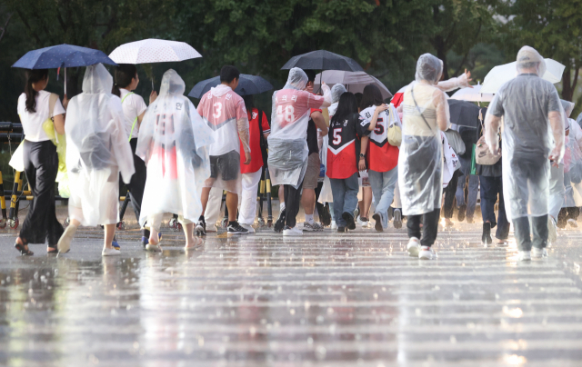 지난해 9월 갑작스러운 폭우에 서울 잠실야구장 인근에서 시민들이 우비를 입고 걸어가고 있다.연합뉴스