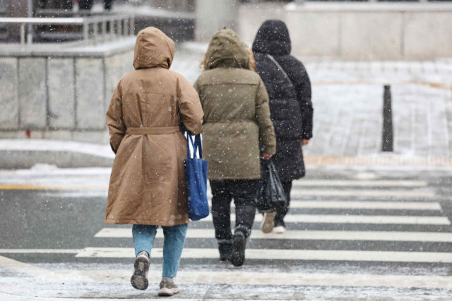 눈이 내린 지난 9일 오전 서울 중구 을지로입구역 인근에서 시민들이 외투 모자를 쓰고 출근하고 있다. 연합뉴스