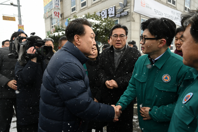 윤석열 대통령이 23일 충남 서천군 서천읍 서천특화시장 화재 현장에서 한동훈 국민의힘 비상대책위원장과 함께 현장을 점검한 뒤 떠나며 악수하고 있다. 서천=연합뉴스