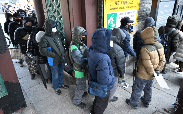 서울의 체감온도가 영하 21.7도까지 떨어진 23일 서울 종로구 탑골공원 인근에서 노인들이 무료급식소에서 점심 배식을 받기 위해 길게 줄을 서 있다. 권욱 기자