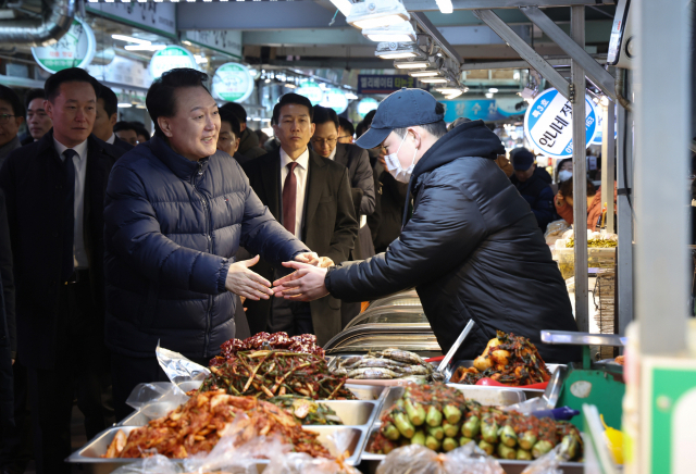 윤석열 대통령이 25일 경기도 의정부시 의정부제일시장을 찾아 반찬가게를 운영하는 한 청년사장을 격려하고 있다. 의정부=연합뉴스