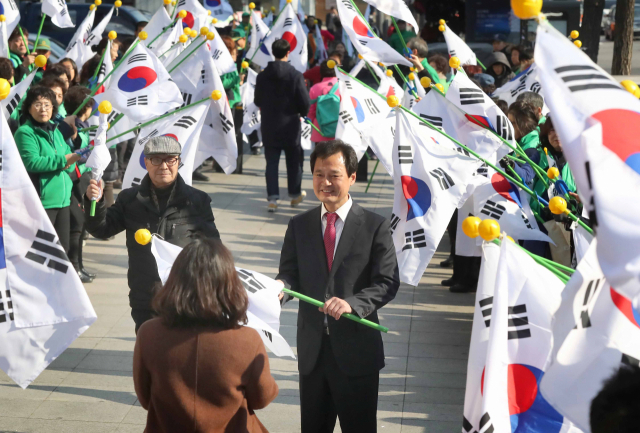 박겸수 전 강북구청장이 2017년 2월 28일 서울 강북구청 사거리에서 열린 나라사랑 태극기 달기 캠페인에서 시민들에게 태극기를 나눠주고 있다. 연합뉴스