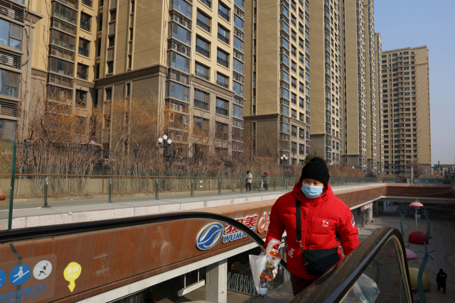 29일 중국 베이징에서 한 여성이 부동산 개발업체 헝다그룹이 지은 주거용 건물 인근에 설치된 에스컬레이터를 올라가고 있다. 연합뉴스