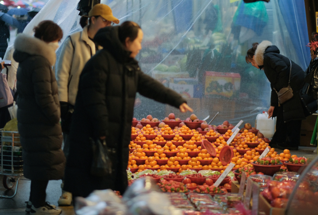 서울 시내 전통시장에서 시민들이 과일을 고르고 있다. 겨울철 대표 과일인 귤 가격은 고공행진을 이어가고 있다. 연합뉴스