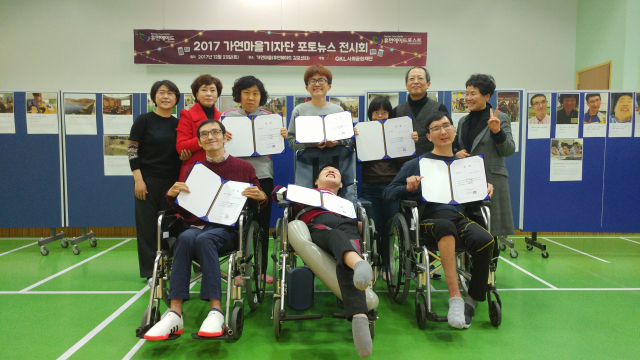 2017년 12월 중장애인시설 ‘가연마을’에서 열린 포토뉴스 전시회에서 김동현(뒷줄 오른쪽 두 번째) 휴먼에이드 대표가 전시회 참여자들과 기념 촬영을 하고 있다. 사진 제공=휴먼에이드